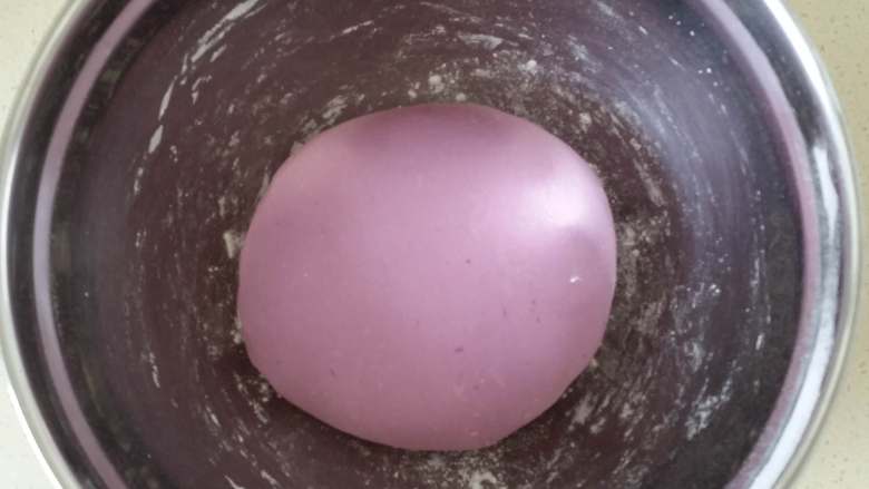 紫薯素包子,搅拌成小面絮状，面板上撒少量干面粉，把面絮倒在面板上，揉搓成不粘手光滑的面团。如果感觉粘手，就继续加干面粉。
