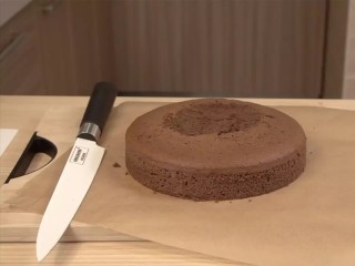 可可戚风巧克力围边奶油蛋糕,完全冷却后，用手把蛋糕剥离模具脱模，切掉顶部凸起部分