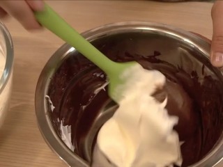 可可戚风巧克力围边奶油蛋糕,将1/3蛋白霜加入到面糊里，翻拌均匀（不要画圈搅拌）
