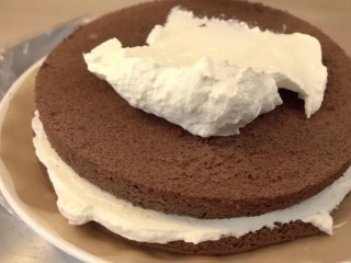 可可戚风巧克力围边奶油蛋糕,将蛋糕的烘烤面放最下层，涂上一层奶油。四周可以稍微溢出来些，再放上第二层蛋糕（烘烤时的底层做顶部），再涂上奶油