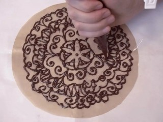 可可戚风巧克力围边奶油蛋糕,再剪裁一张圆形的烘焙纸，大小和蛋糕一样，在一张A4纸上画上你喜欢的图案，烘焙纸覆盖在图案上，用巧克力描下来，也是放置几分钟，等巧克力稍凝固