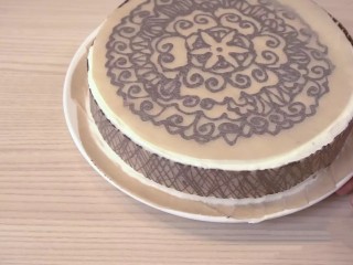可可戚风巧克力围边奶油蛋糕,等巧克力稍凝固，但没有完全变硬时，把花纹粘在蛋糕上，再放入冰箱冷藏5-10分钟