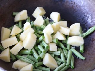 土豆豆角焖饭,放入土豆块、豆角段翻炒均匀；