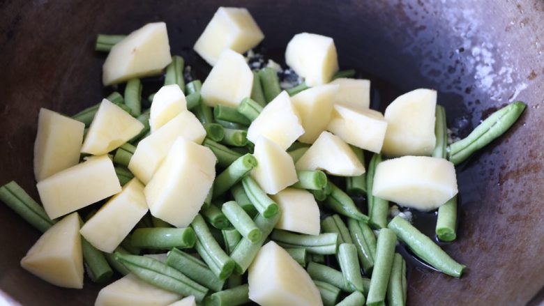 土豆豆角焖饭,放入土豆块、豆角段翻炒均匀；