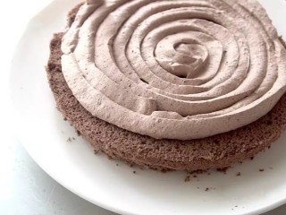 滴落巧克力蛋糕,将巧克力奶油装入裱花袋，以漩涡状挤在第一层蛋糕胚上，用奶油抹刀涂抹平整