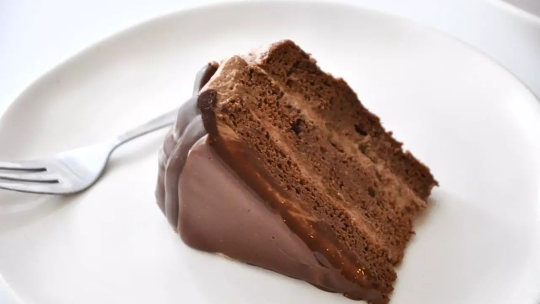 滴落巧克力蛋糕,将剩余的巧克力甘纳许，淋在蛋糕表面（淋面用的巧克力甘纳许需要比周围滴落用的稍稀一些，如果开始凝固变稠，可以微波5-10秒来融化）