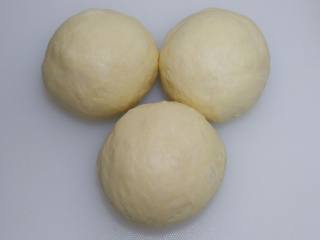 蔓越莓椰蓉面包卷,平均分成三等份，滚圆，盖保鲜膜室温醒发15分钟。