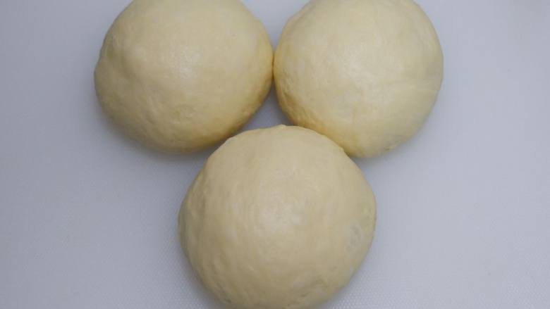 蔓越莓椰蓉面包卷,平均分成三等份，滚圆，盖保鲜膜室温醒发15分钟。