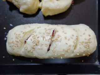 蔓越莓椰蓉面包卷,发酵至1.5-2倍大，取出刷鸡蛋液，撒上适量的白芝麻。用锋利的小刀割出三道口，要深一点割到看见椰蓉馅儿