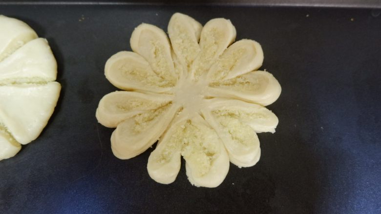 椰蓉菊花面包,每两个一组，向外侧翻，翻成切口朝上，露出椰蓉馅，依此类推，全部翻好，进行2次发酵。