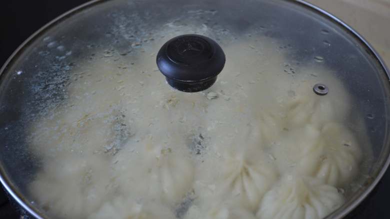 冰花水煎包,直到听到锅里刺啦刺啦的声音，面粉水快收干时，打开锅盖看看。