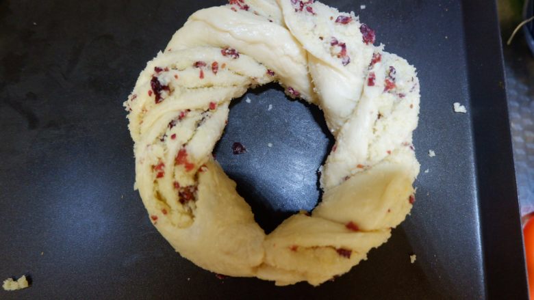 椰蓉蔓越莓花环面包,拧到最后，底边捏紧，轻轻放入烤盘，整理成圆形