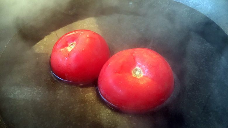 番茄鸡蛋青豆,在番茄的顶部划一个十字口，放在开水里焯烫一下，然后去皮。