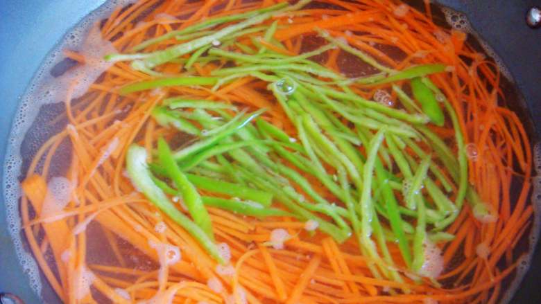 蕾丝芥末卷,胡萝卜放入开水锅里烫软，最后放入青椒丝稍微烫一下捞出过凉水，沥干水份。