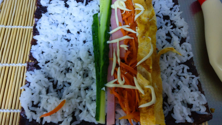 简单易学的寿司,依次将黄瓜条，火腿条，鸡蛋条，和胡萝卜丝放到铺好的米饭上，再加入适量的<a style='color:red;display:inline-block;' href='/shicai/ 4856'>沙拉酱</a>。
