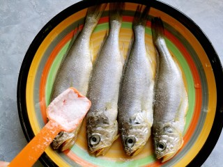 干炸黄花鱼,在黄花鱼身上洒上1小勺盐。