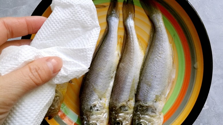 干炸黄花鱼,然后挑去葱姜，用厨房纸将鱼擦去水份。