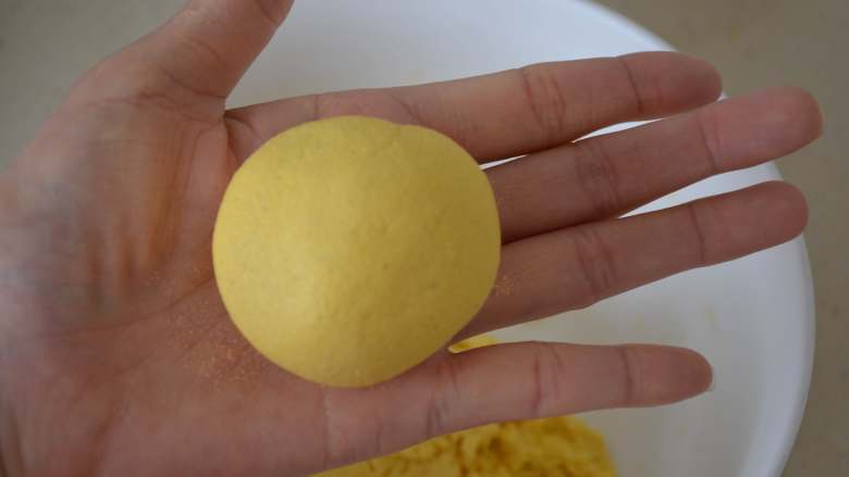 玉米发面饼,现在的状态略微粘手，用两个手掌心轻轻搓圆。如果感觉粘手严重，可以在手上少抹点干面粉继续搓。