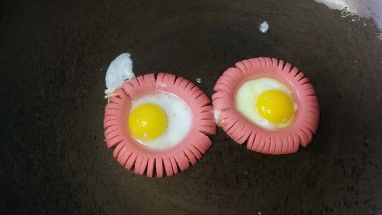 太阳花煎蛋,中间打入鹌鹑蛋，用鸡蛋的话先打鸡蛋打入碗中，再用勺子把蛋黄舀出来放入火腿肠中间。