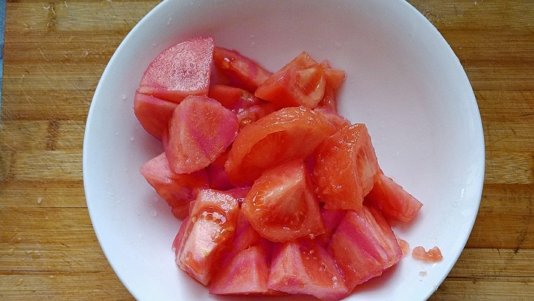 西红柿炖牛肉,去皮的西红柿切成小块放在碗中备用。