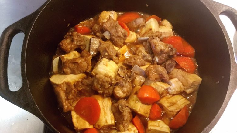 铸铁锅豆腐焖排骨,小心地把排骨捡到表面上来，把豆腐没入汤汁中继续焖烧5分钟。关火，别揭盖。