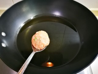 外酥里嫩馒头渣肉圆,锅中烧热油，用勺子滚动圆肉糊下锅炸