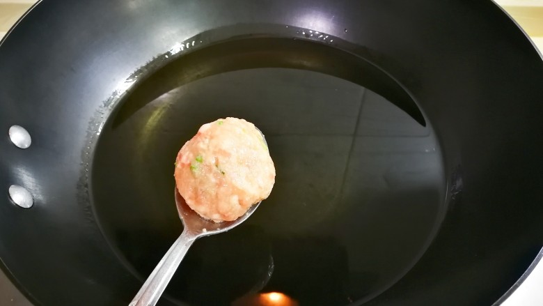 外酥里嫩馒头渣肉圆,锅中烧热油，用勺子滚动圆肉糊下锅炸