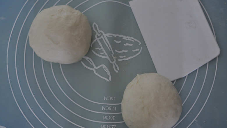 椰蓉面包卷,取出发酵好的面团，在案板上揉去空气，分为2份，盖上保鲜膜松弛15分钟