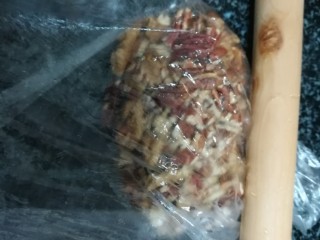 香蕉芝麻坚果仁馅饼,把碧根果仁和核桃仁放在保鲜袋里，用擀面杖擀成碎。