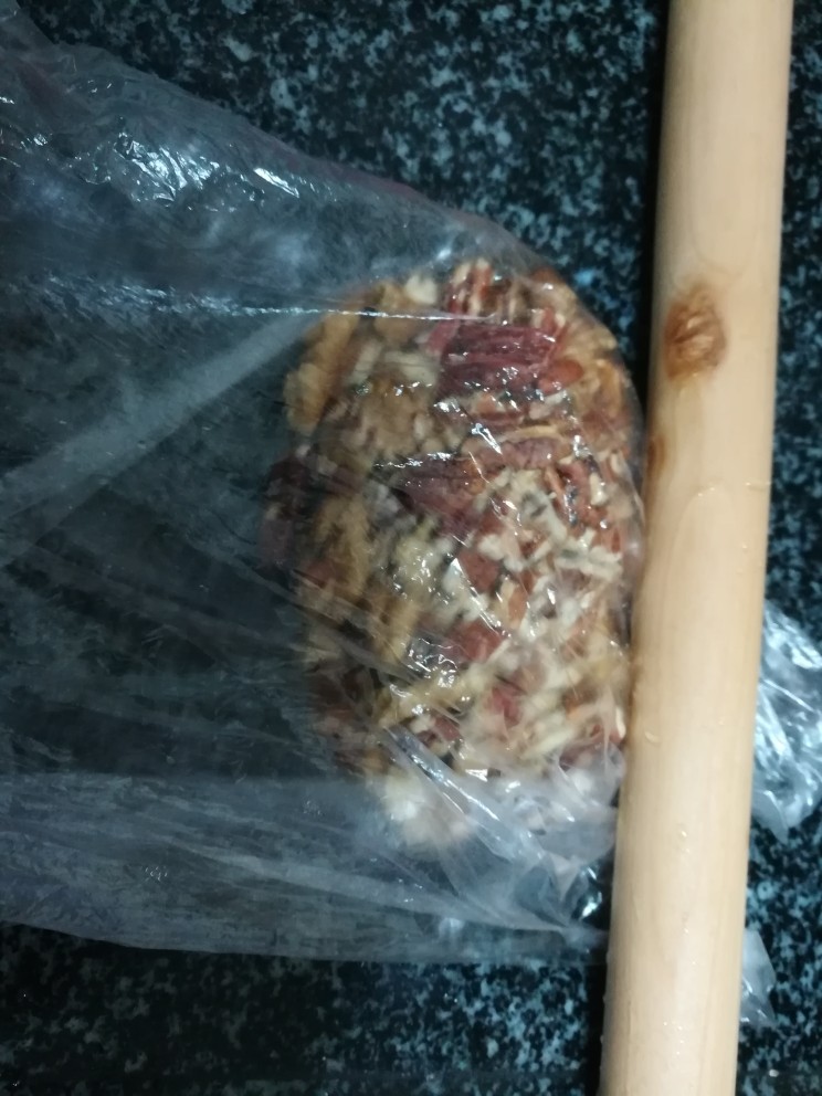香蕉芝麻坚果仁馅饼,把碧根果仁和核桃仁放在保鲜袋里，用擀面杖擀成碎。
