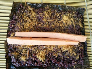 黑米寿司,火腿肠用刀切成条，如图中放在中间