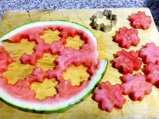 西瓜花篮,西瓜洗净沥干水分切开取大的3分之二处再先切下1.5厘米厚度的西瓜片用花朵模具压出漂亮的西瓜花