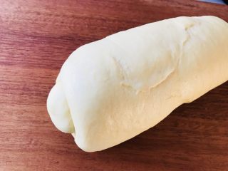 奶酪吐司（面包机版）,用擀面杖将面团擀成椭圆形，翻面后卷成如图状继续醒发10分钟。