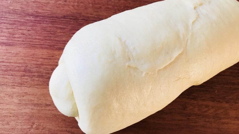 奶酪吐司（面包机版）,用擀面杖将面团擀成椭圆形，翻面后卷成如图状继续醒发10分钟。