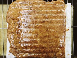 蜜汁猪肉脯,拿出来刷一层蜂蜜水，然后用刚才剪下的油纸铺上，给肉片翻面，再刷一层蜂蜜水，放入烤箱再烤5分钟后取出