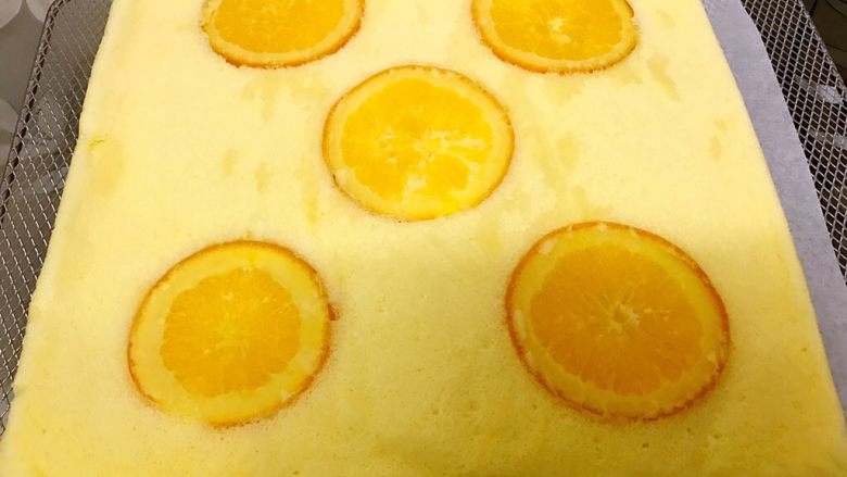 橙香蛋糕卷,底下铺油纸把蛋糕倒扣在烤网上趁热撕下油纸