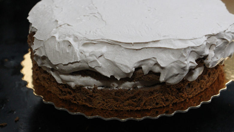 8寸脏脏蛋糕,将另一片蛋糕片盖上去，表面抹上剩余的巧克力奶油霜，同样不需要抹平，大概平整稍微乱乱的最好。