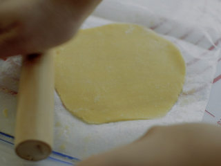 Q弹港式菠萝包,把装面团的保鲜袋撕开，撒上面粉，把酥皮放在保鲜袋上擀成饺子皮那样的面片，也可以用保鲜膜。