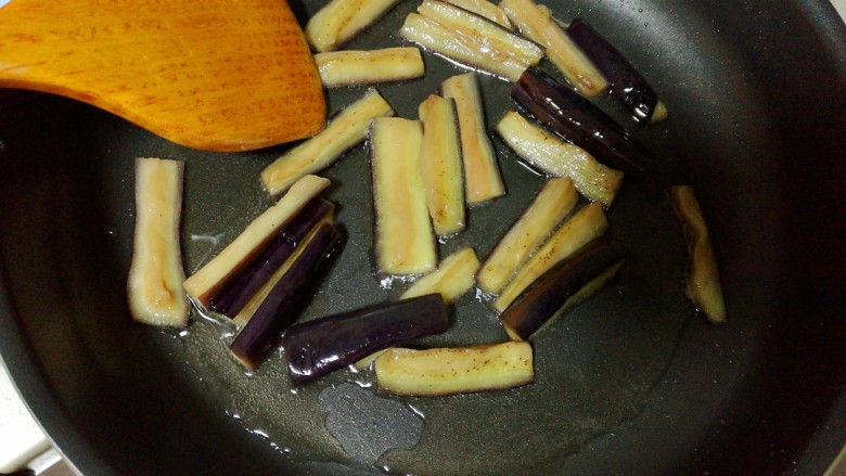 豆角烧茄子,锅中放油烧热，放入腌好的茄条，煸至茄子变色变软后盛出。