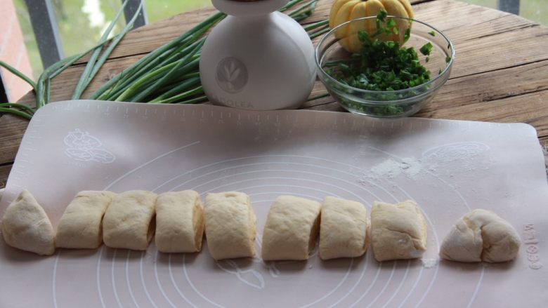 南瓜香葱饼,取出面团，蘸少许干面粉将面团揉圆排气，将面团揉成长条，切成70克左右的小面团