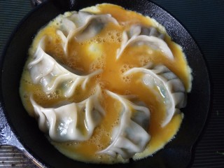 抱蛋煎饺,饺子煎熟，将蛋液倒入锅中。
