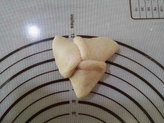好看又好吃的——褐麦红豆沙三角包,将三个角相互折叠，并捏紧收口处，否则在发酵的过程中会裂开的。依次将其余的小面团都做好。