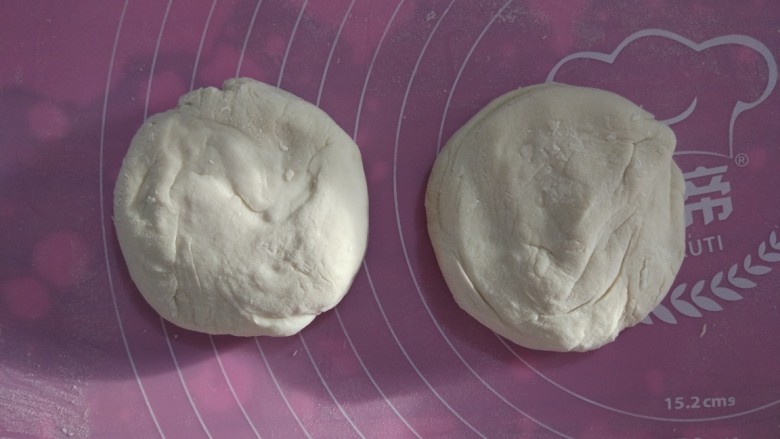 家常烙饼,取出面团，揉面垫撒少许手粉，不需要揉制面团，只需要稍微整形，分成两份。整圆，按扁。