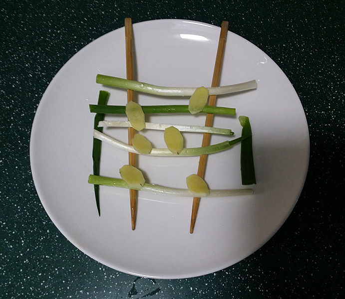 剁椒鱼头,取一大盘子上面架起一双筷子、放上洗净的葱段和姜片，也是达到去腥增香的作用