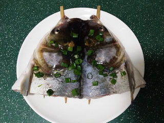 剁椒鱼头,将腌好的鱼头正面朝上架在筷子上、再撒些葱花