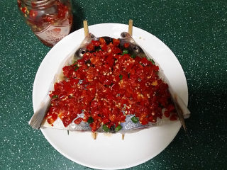 剁椒鱼头,稍后用勺子将剁椒均匀地铺在鱼头上面、然后滴些料酒，可起到进一步去除腥味和剁椒经腌制后产生的异味