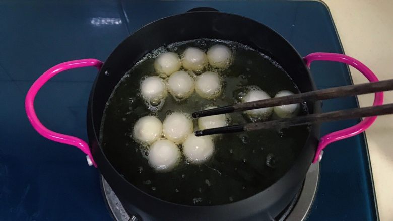 干菜炒汤圆,把汤圆用筷子挨个放入，并用筷子不断翻拌，以防粘连
