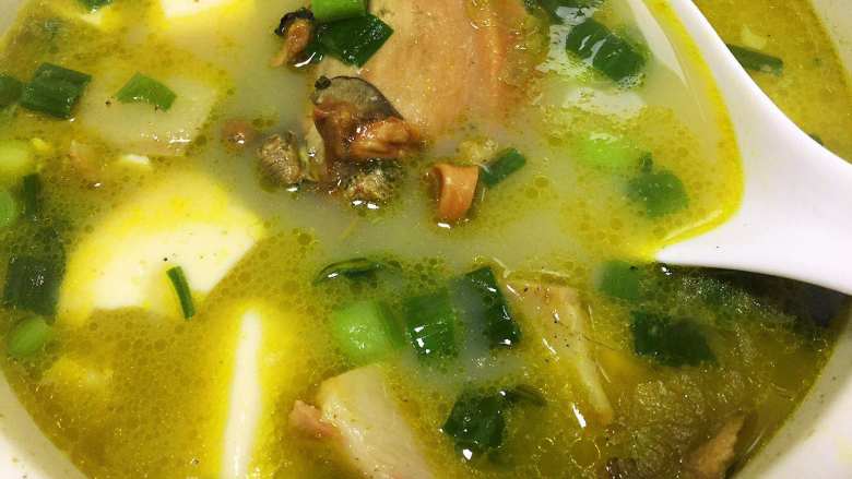 河蚌咸肉豆腐汤,撒入青蒜，即可食用。