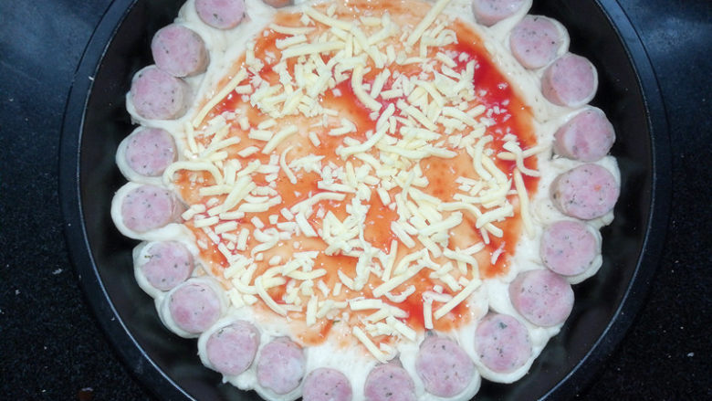 满园春色香肠披萨,将酱料抹匀后，铺上一层马苏里拉芝士。