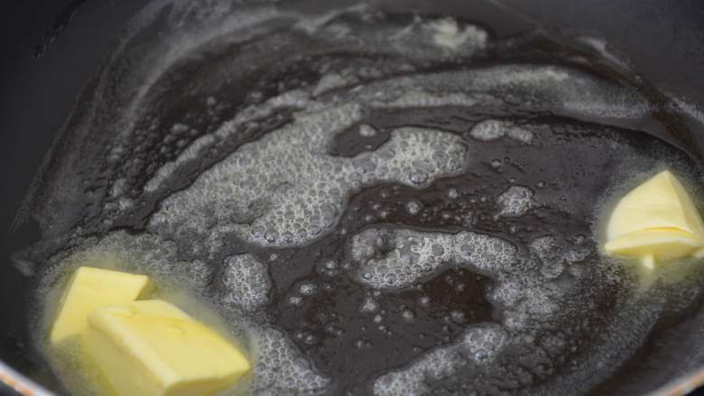 花生牛轧糖,把黄油放到平底不粘锅内，小火慢慢融化。